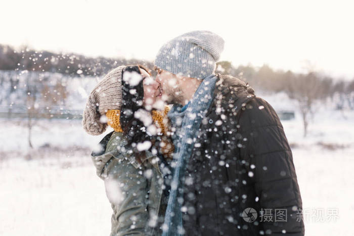 快乐的女人和男人在降雪中亲吻和拥抱,一起度过彼此的雪生活冬天.