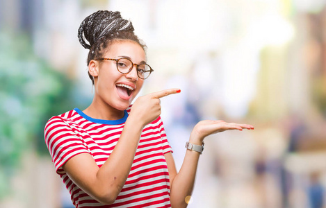 年轻的头发非洲裔美国女孩戴着眼镜在孤立的背景下惊讶和微笑的相机，同时呈现手和手指。
