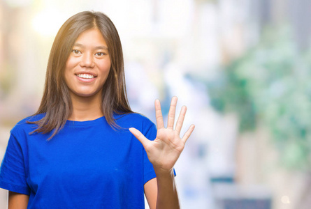 年轻的亚洲女人，在孤立的背景下，用手指第五，微笑着自信和快乐。