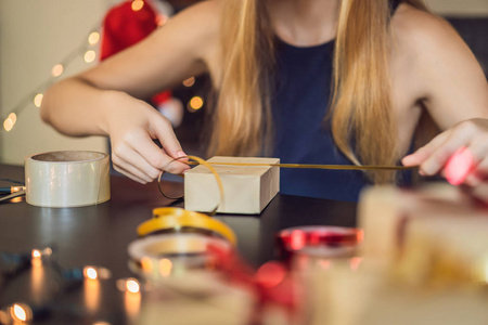 裁剪的妇女包装圣诞礼物在工艺纸桌上。
