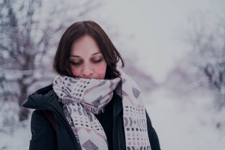 这个女孩在冬天的树林里休息。 在冬天的公园里，年轻的女人在雪地里散步