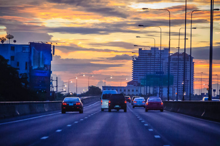 美丽的公路在城市中流动的交通在黄昏日落与黄色的天空背景。