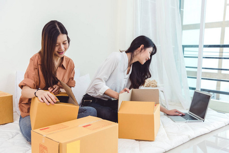 年轻的亚洲女性创业小企业企业家中小企业分销仓库与包裹信箱。 业主家庭办公室的概念。 在线营销和产品包装和交付服务。