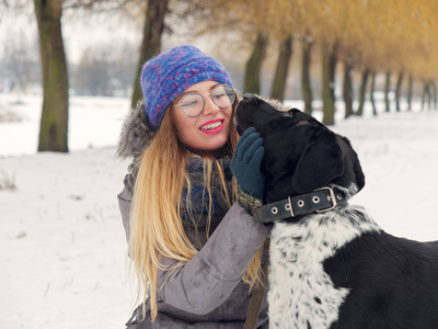 美丽的女孩在雪地里拥抱一只狗