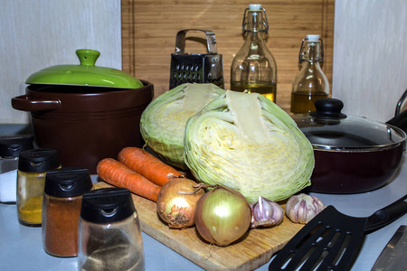 在平底锅中煮素汤的新鲜原料。 卷心菜胡萝卜洋葱和大蒜在锅和锅的背景上。