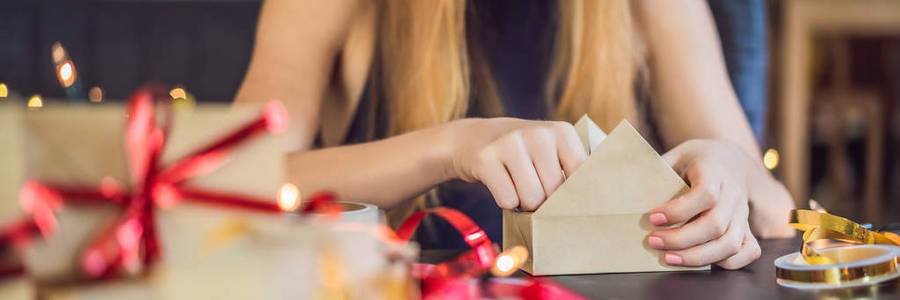裁剪的妇女包装圣诞礼物在工艺纸桌上。