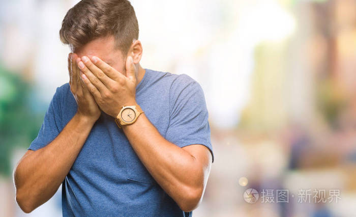 年轻的英俊男子在孤立的背景上,悲伤的表情覆盖着脸,双手哭泣.