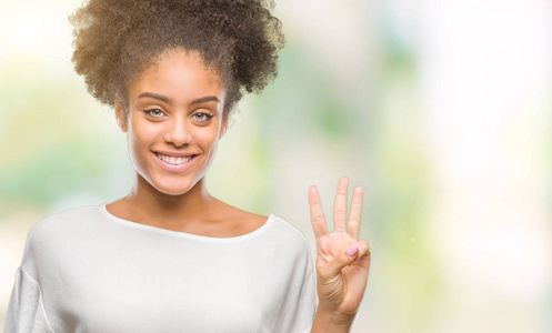 年轻的非洲美国妇女在孤立的背景显示和指着第三个手指，同时微笑自信和快乐。
