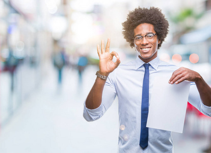 美国黑人男子拿着空白纸合同在孤立的背景上做OK签名手指优秀的符号