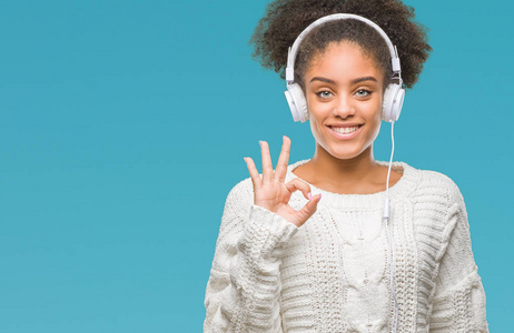 年轻的美国女性戴着耳机在孤立的背景下做OK标志手指优秀的符号