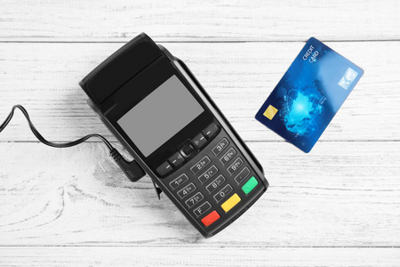白色木制背景下的现代支付终端和信用卡