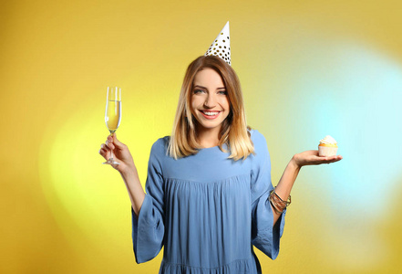 幸福女人的肖像，杯子里有香槟，彩色背景上有美味的纸杯蛋糕