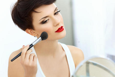 化妆刷美女。红唇黑发女人的天然妆容。