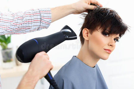 理发师使用烘干机在妇女湿发沙龙。 短发。