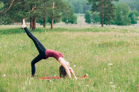 运动女孩在田野公园的树林里做运动。 瑜伽运动健康