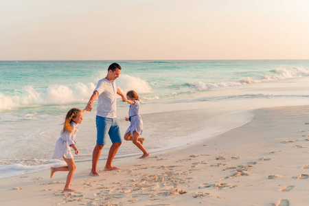 家人在加勒比岛上的白色热带海滩上行走
