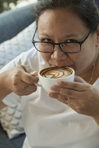 在咖啡店喝咖啡的漂亮女人的户外画像。焦点