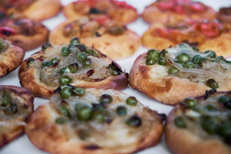在白色背景上关闭新烘焙的迷你披萨球。 传统的西班牙糕点和蔬菜。