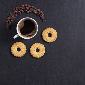 咖啡杯和短饼干在黑色石头背景顶部视图与复制空间。