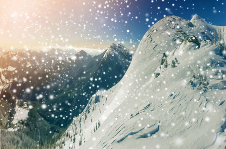美丽的冬季景观。 陡峭的山坡，白色的深雪远处的山脉全景，大的雪花和明亮的阳光照射在蓝天上，五颜六色的复制空间背景。