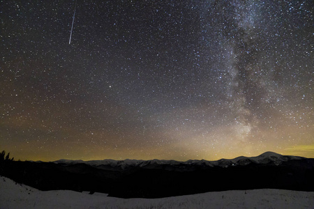 冬夜神奇星空黑暗天空的壮丽景色。 银河系和陨星越过壮丽的山脊雪顶峰。 令人叹为观止的美景和大自然的魔力。