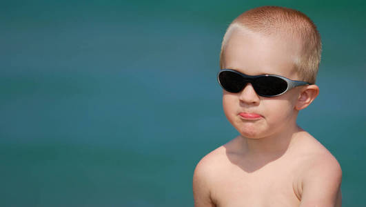 在海边戴太阳镜的金发小男孩肖像