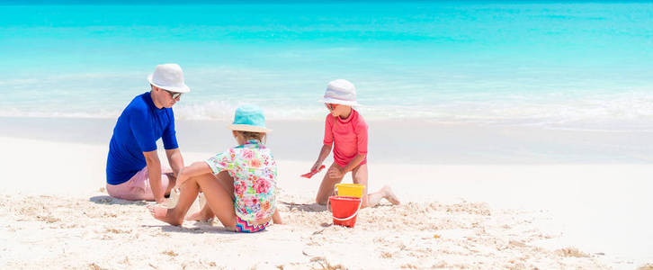 父亲和小女儿做沙子城堡在热带海滩
