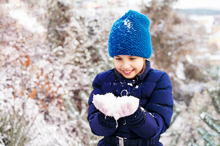 美丽的年轻女孩穿着蓝色的衣服在户外玩雪。