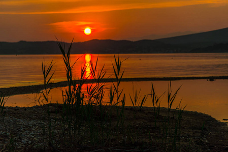 傍晚夕阳西下，天空中长满了青草和湖水，还有夕阳的倒影