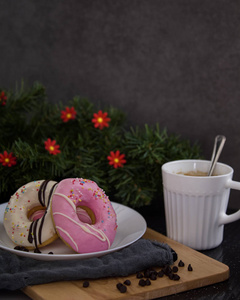 粉红色甜甜圈在盘子里，咖啡在黑暗的木制背景下，黑暗的食物摄影概念