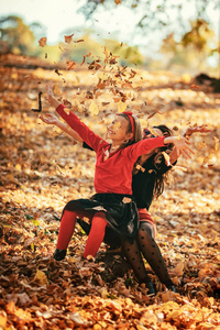 年轻时尚的母亲和快乐的女儿在秋天的森林里享受日落