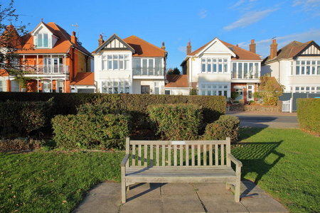 一排五颜六色的房子坐落在海上上，在英国海上的前景里有一个木制长凳