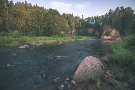 拉脱维亚阿马塔河中的水流，夏季有砂岩峭壁和绿色树叶