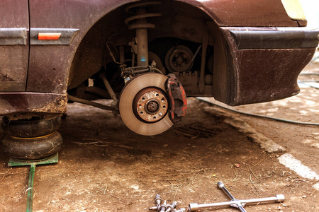 带有拆卸车轮的客车是在带有裸制动系统的液压千斤顶上。 旧磨损生锈的汽车刹车盘，技术过时。 软焦浅场深