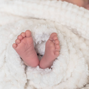 用毯子把新生婴儿的脚关起来。 宏观照片小男孩脚趾舒适的毛绒衬里可爱的纺织品