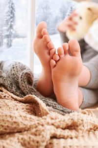 s foots are on a window sill with wool plaid and yarns.