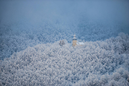 雪覆盖森林树木和景观与教堂在阿尔卑斯山