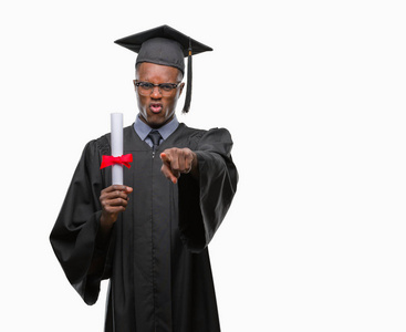 年轻毕业的非裔美国人，他拿着学位在孤立的背景上，手指着相机，向你手势正面和自信的手势
