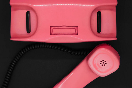 黑色背景表面旧的和脏的粉红色复古电话的俯视图