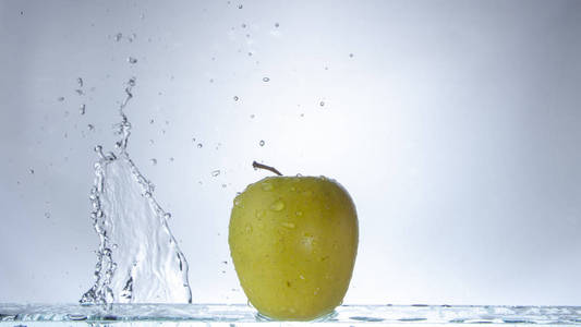 绿色的苹果在明亮的背景和飞溅的水关闭