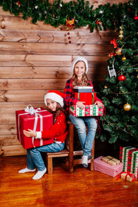 圣诞快乐, 节日快乐。两个可爱的小孩与目前礼品盒附近的树室内