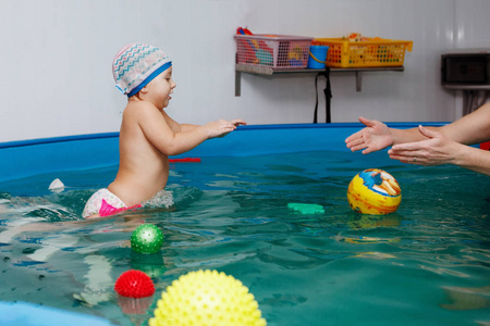 婴儿学会在游泳池里游泳。 健康生活方式水康复水疗法。