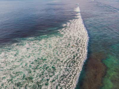 在海水中乘浪冲浪者的鸟瞰图