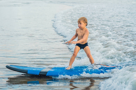 小男孩在初学者登上热带海滩冲浪。