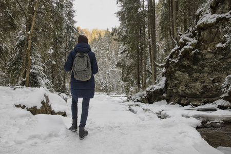 带背包的女孩站在一片雪林里。 冬天。