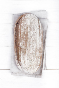 一整条自制的黑色面包在木制背景上特写。 文本空间