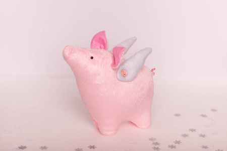 一个美丽的小猪天使，用雪花在白色粉红色的背景上手工站立