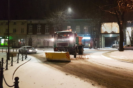 一辆配有大型推土机的技术服务车从雪中清洁城市道路，并用沙子喷洒。 由于夜间城市的暴风雪，打开通道。 冬季阻塞