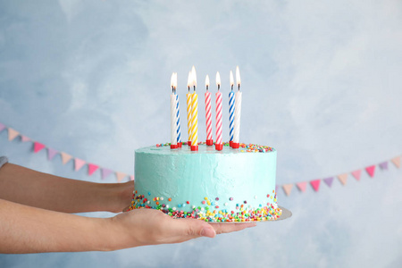女人拿着新鲜美味的生日蛋糕，上面有彩色背景的蜡烛