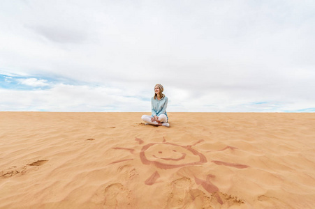 年轻的女人坐在沙丘上放松和享受假期休息。 旅游心理健康概念